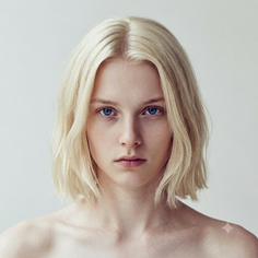 Person with blonde hair and blue eyes looking directly at the viewer