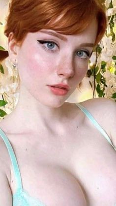 Woman with red hair and blue eyes wearing a light blue bra with cleavage