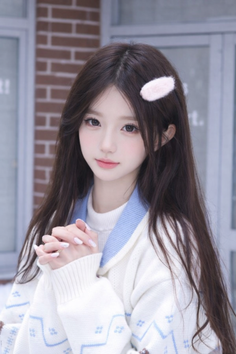 Woman with long dark hair and a white sweater with blue patterns