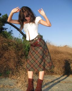 Woman in a plaid skirt and white top outdoors under a clear sky