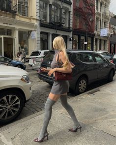 Woman with blonde hair in a mini skirt and thigh-high socks walking on a city street