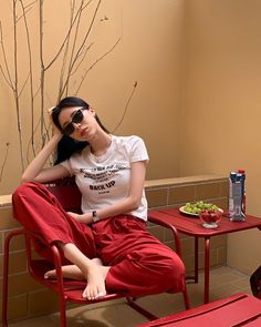 Woman in red pants and a white t-shirt sitting outdoors with bare feet