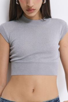 Woman in a grey crop top and jeans with exposed midriff