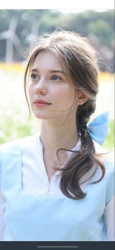 Woman with a blue bow in her hair, wearing a white shirt outdoors