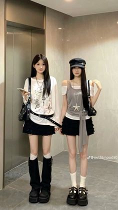 Two women in dark skirts and platform shoes standing indoors
