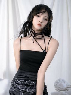 Woman with long black hair and a black top with a choker and lip piercing