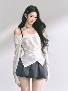 Woman with long black hair wearing an off-shoulder top and pleated skirt