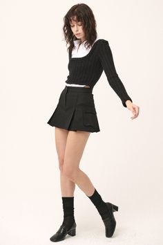 Woman in a black mini skirt and long sleeve top with a white collar