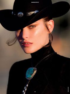 Woman in a black cowboy hat and turtleneck with a turquoise bolo tie