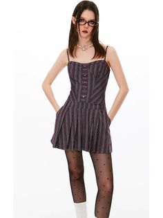 Woman in a striped dress, polka dot tights, and glasses on a white background