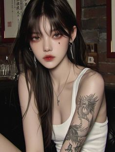 Woman with long dark hair and a dragon tattoo wearing a white tank top