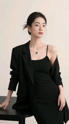 Woman in a black dress and blazer with an updo and jewelry