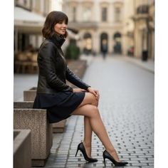Woman with short hair in a leather jacket and mini skirt sitting on a street bench