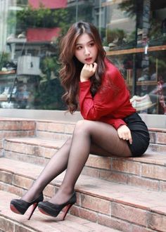 Woman in a red shirt and black skirt sitting on brick steps