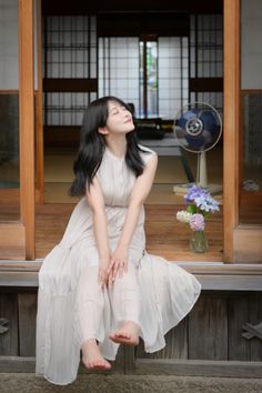 Woman in a light dress sitting barefoot in a traditional Japanese house