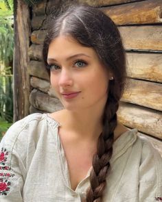 Woman with a long braid and embroidered shirt smiling outdoors