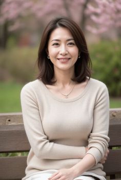 Woman with short hair and a beige sweater sitting on a park bench