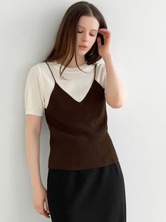Woman with long brown hair wearing a white t-shirt and brown camisole