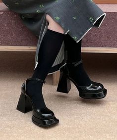Person wearing black socks and platform mary jane heels with a dark dress
