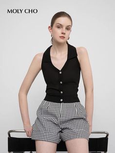 Woman in a black collared top and houndstooth shorts in a studio