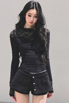 Woman with long black hair wearing a black lace top and shorts