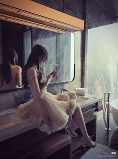 Woman in a tulle dress and high heels sitting on a bathroom counter