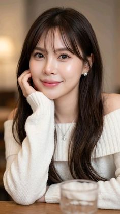 Woman with long dark hair and bangs wearing an off-shoulder sweater