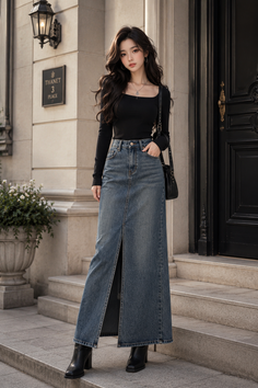 Woman with long dark hair wearing a black top and denim skirt outdoors