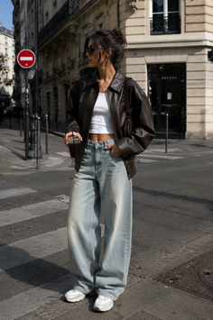 Woman in a brown leather jacket and baggy jeans on a city street