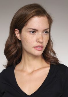 Woman with freckles and brown hair wearing a black v-neck shirt