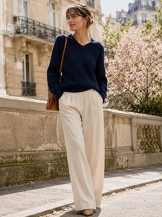 Woman in a navy sweater and wide leg pants walking on a city street