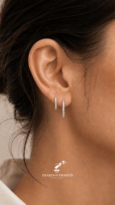 Close up of an ear with two diamond hoop earrings