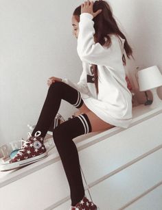 Person in a white hoodie and thigh-high socks sitting on a dresser