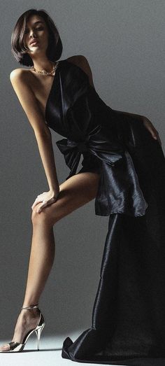 Woman in a black dress and gold necklace posing in a studio