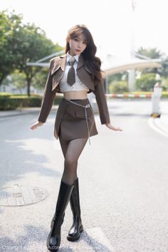 Woman in a brown cropped jacket and mini skirt with black boots outdoors