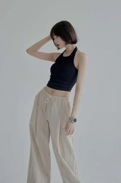 Woman with short black hair in a black halter top and wide leg pants