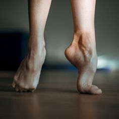 Bare feet on tiptoes on a wooden floor, captured in a close-up shot