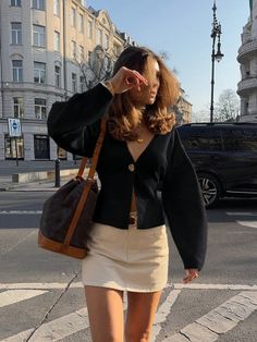 Woman in a black cardigan and mini skirt walking on a city street