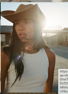 Woman in a cowboy hat and white tank top with backlight from the sun