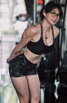 Woman with a muscular physique wearing a sports bra and shorts in a gym