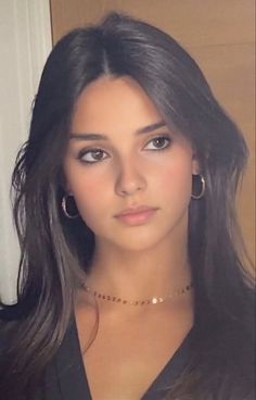 Young woman with long dark hair wearing hoop earrings and a choker