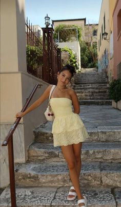 Woman in a yellow strapless dress and white sandals on stone stairs