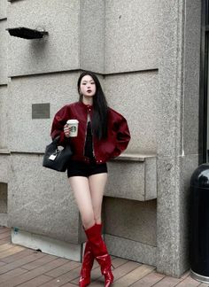 Woman in a red jacket and red boots holding a Starbucks cup outdoors