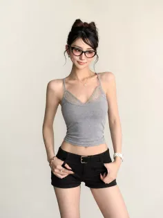Woman in a gray lace camisole and black shorts posing indoors