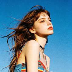 Woman with long hair and freckles looking up against a clear blue sky