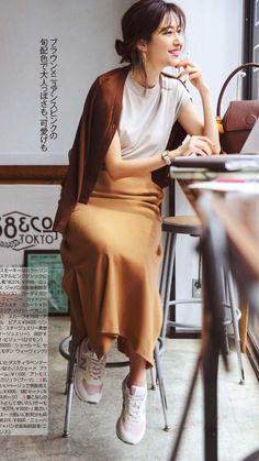 Woman in a brown cardigan and midi skirt sitting indoors