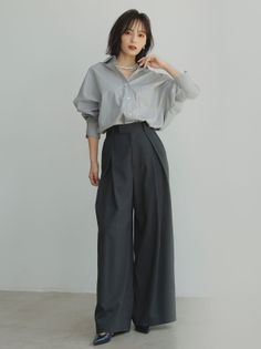 Woman with short hair wearing a gray shirt and wide leg pants