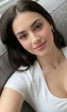 Woman with dark hair wearing a white t-shirt and gold necklace