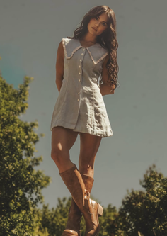 Woman in a light blue mini dress and brown boots outdoors