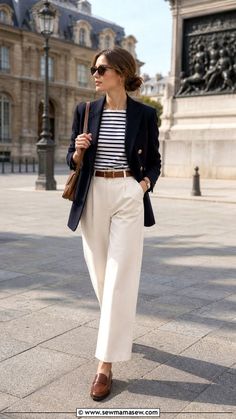 Woman in a navy blazer and striped shirt walking outdoors